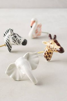 four different types of giraffe, zebra and elephant toothbrushes on a white surface