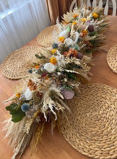 the table is set with flowers and straw placemats on top of each other