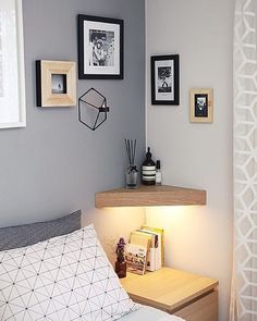 a bedroom with gray walls and pictures on the wall above the bed, along with a small night stand