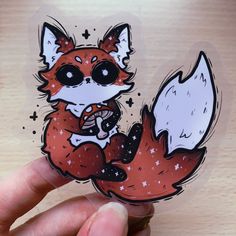 a hand holding a sticker with an image of a fox