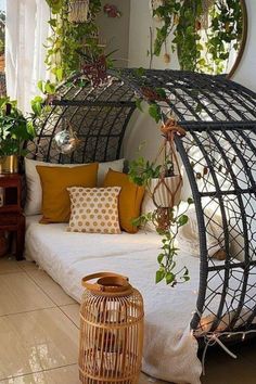 a bed with lots of plants hanging from it's sides and pillows on the floor