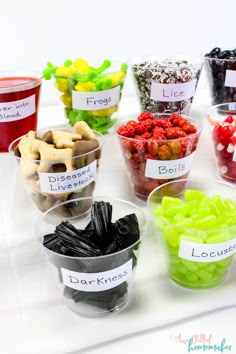 a table topped with cups filled with different types of candies and candy bar toppings