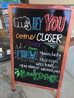 a sign that is on the sidewalk advertising book store closing hours and books to go