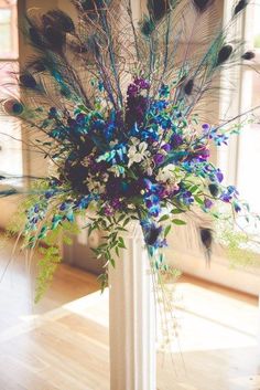 a vase filled with lots of purple and blue flowers on top of a wooden floor