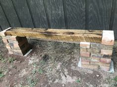 a wooden bench made out of bricks sitting in the dirt next to a fenced area