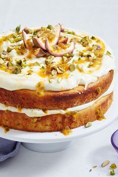 a cake with white frosting and fruit toppings on top sitting on a plate