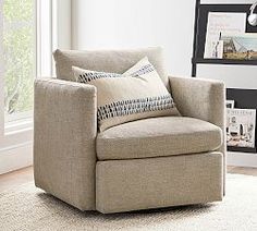 a living room with a chair, rug and pictures on the wall behind it in front of a window