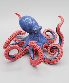 an octopus figurine sitting on top of a white table next to a red and blue object