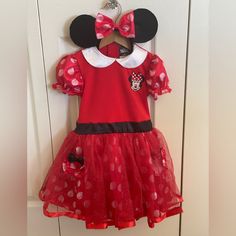 a red minnie mouse dress hanging on a door