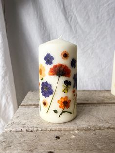 a white candle with flowers painted on it