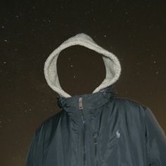 a person wearing a black jacket with a hood on their head is standing in front of the night sky