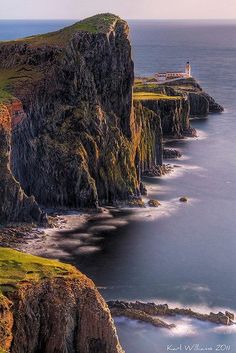 a lighthouse on the edge of a cliff by the ocean