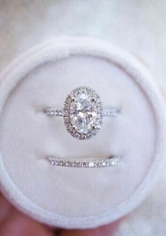 an engagement ring and wedding band in a white velvet box with the diamond set on top