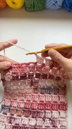 two hands are crocheting together with yarn