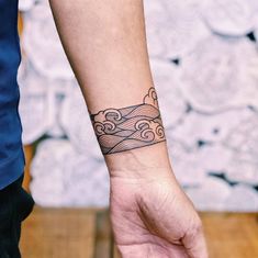 a person's wrist with a tattoo on it that has waves coming out of the ocean