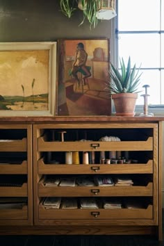 a wooden cabinet with drawers and plants on top