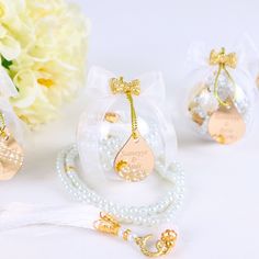 three necklaces with pearls and bows are shown in front of some white flowers on a table