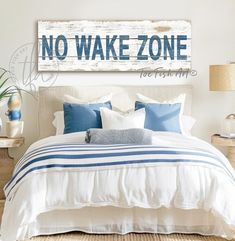 a bed with blue and white pillows on top of it next to a wooden sign that says no wake zone