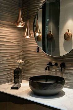 a bathroom sink sitting under a round mirror next to a faucet mounted on a wall