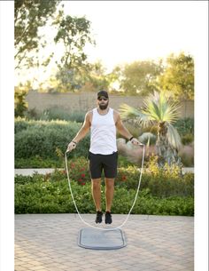 a man standing on top of a metal object in the middle of a courtyard with his hands tied to two ropes