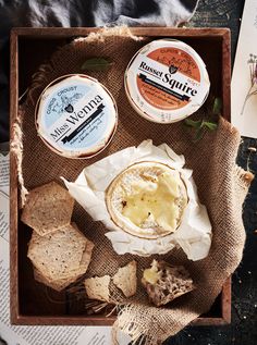 an assortment of cheeses and crackers in a wooden box