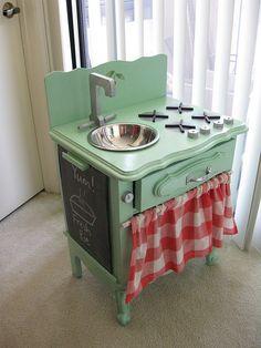 an old fashioned green stove with a sink on it's side in front of a window