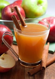 an apple cider with cinnamon sticks and apples in the background