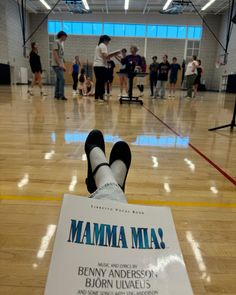 a person sitting on the floor with their feet up in front of a sign that reads mamma mia