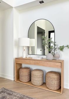 a mirror on the wall above a wooden table with stools and ottomans in front of it