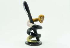 a pen holder with a statue holding a black and white ballpoint pen in it's mouth