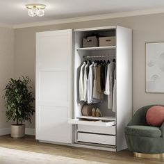 a room with a chair, closet and clothes on hangers next to a potted plant