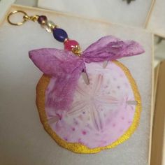 a pink and gold keychain with a starfish on it's side