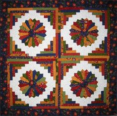 a quilted wall hanging on the side of a building with multiple colors and designs