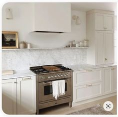 a stove top oven sitting inside of a kitchen next to white cupboards and counter tops