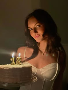 a woman holding a cake with two candles on it