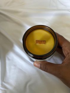 a hand holding a small candle on top of a white sheet