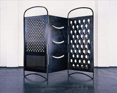 an iron screen with holes in the middle and two sides on each side, sitting against a white wall