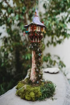 a small tree house with moss growing on it's sides and a clock tower in the background