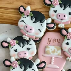 decorated cookies in the shape of farm animals on a table with pink and black accents