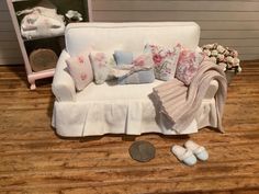 a white couch with pillows and blankets on top of it next to a dime coin