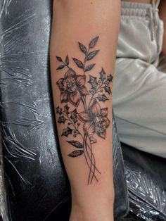 a woman's arm with flowers and leaves tattooed on the left side of her arm