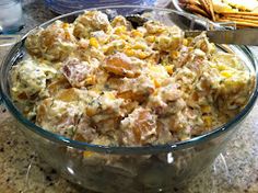 a bowl full of food sitting on top of a counter next to crackers and water