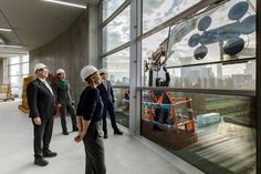 several people in hardhats looking out the window at construction work on an office building