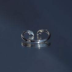 two silver rings sitting on top of a reflective surface