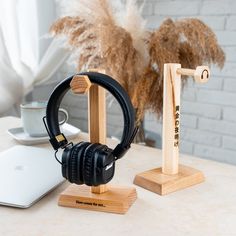 two headphones are sitting on wooden stands next to a laptop