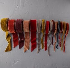 multicolored scarves hanging on the wall in a row with fringes attached to them