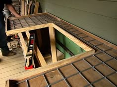 a man is working on building a house with wood and metal grates in the floor