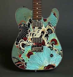 an electric guitar with blue flowers on it's body and neck, sitting in front of a black background