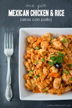 mexican chicken and rice in a white bowl next to a fork, knife and spoon