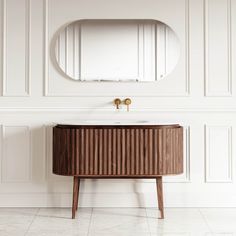 a bathroom vanity with a round mirror above it and a wooden cabinet in the corner